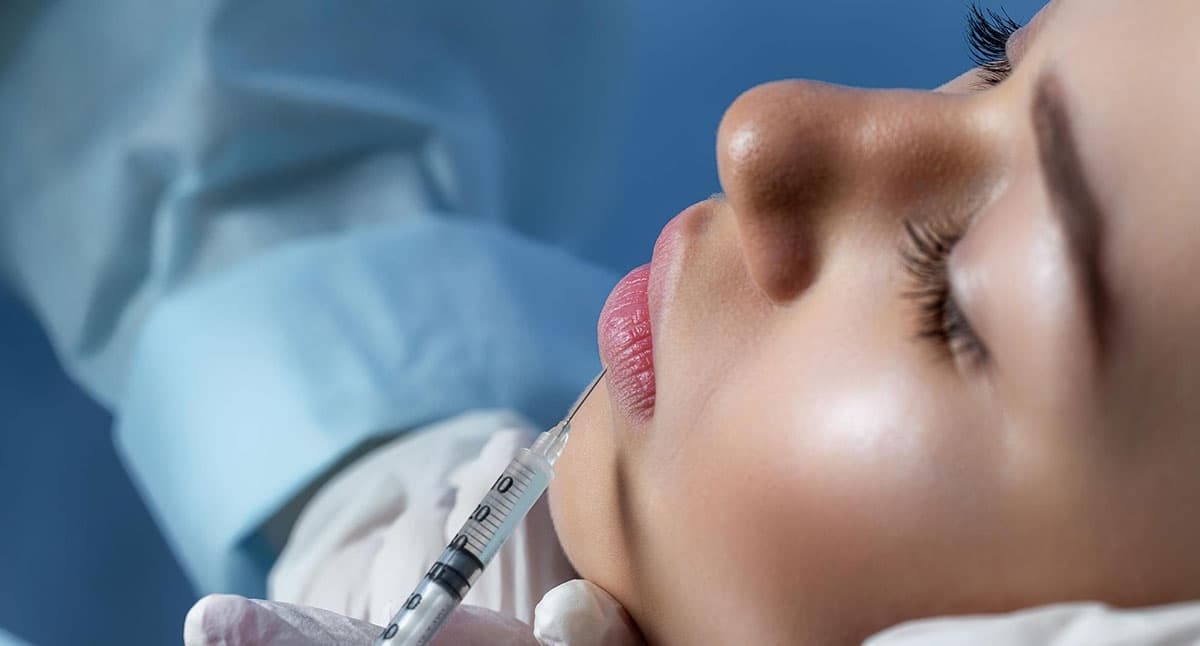 Aesthetic doctor injecting lip filler