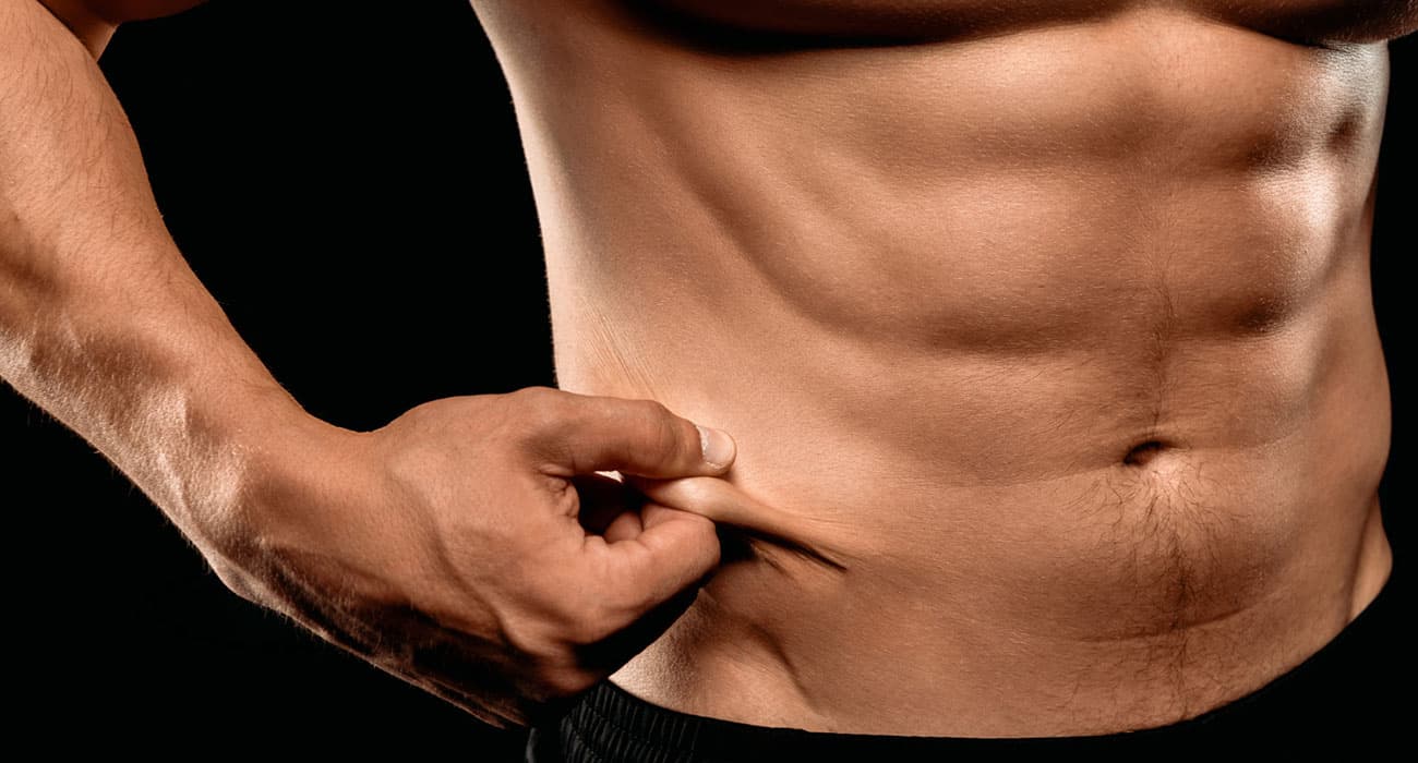 Toned male abdomen with stubborn fat being pinched at the waist